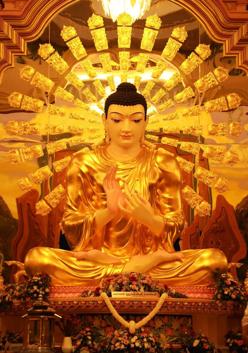Golden statue of the Buddha seated in meditation, with a radiating golden halo behind