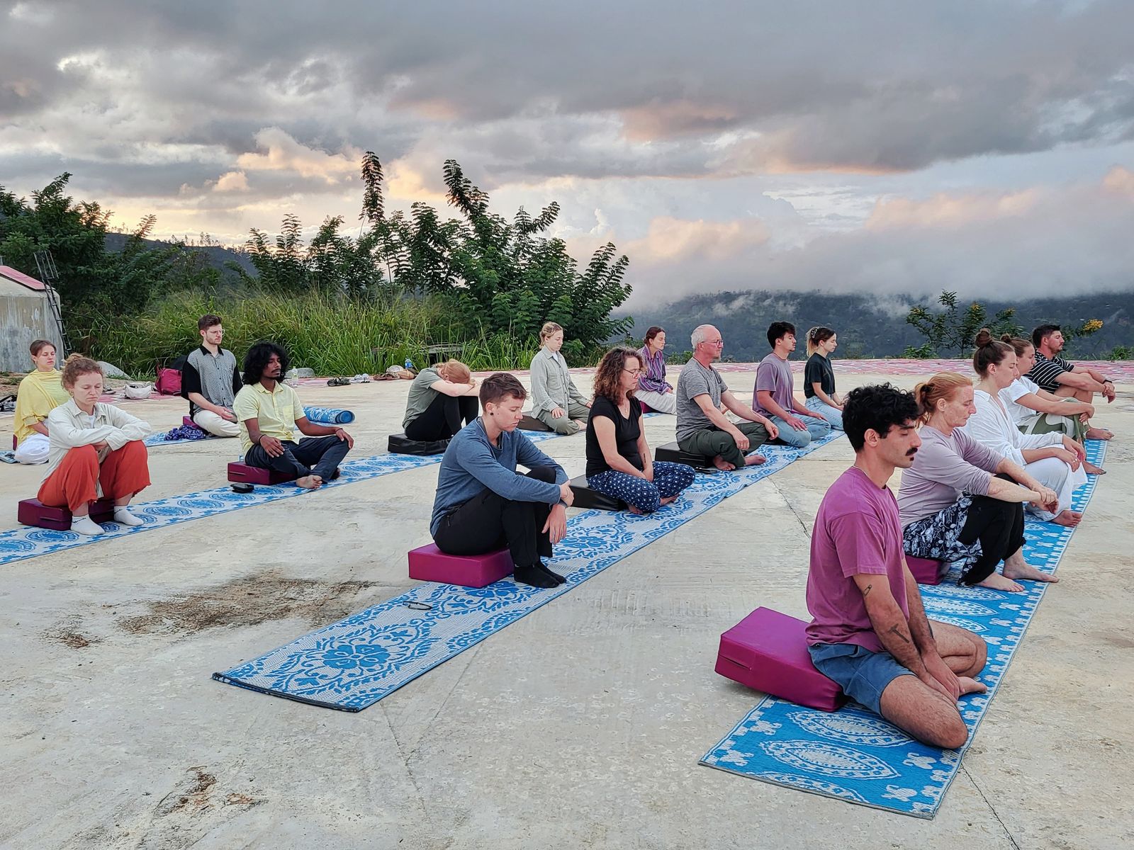 Visitors meditating together on an open terrace