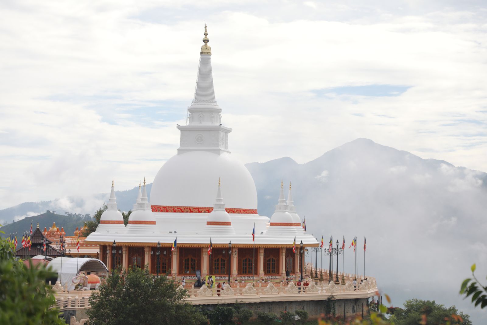 The Seven Buddhas Great Stupa standing on the Bodhiparvatha hilltop, with misty mountains behind